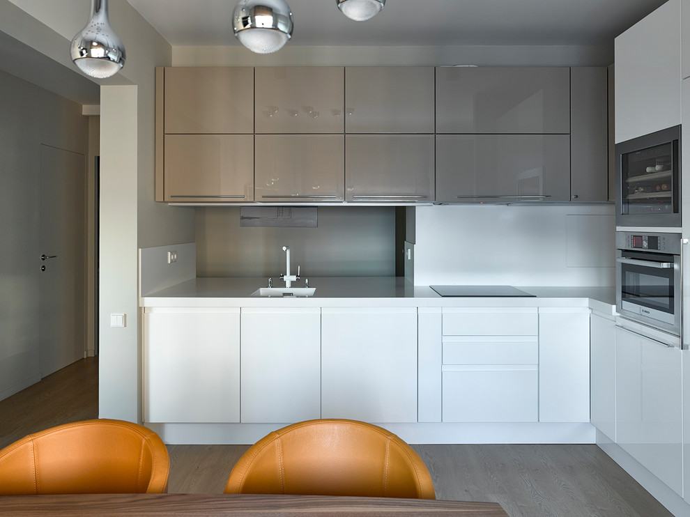Photo of a contemporary l-shaped eat-in kitchen in Moscow with an integrated sink, flat-panel cabinets, white cabinets, white splashback, stainless steel appliances and no island.
