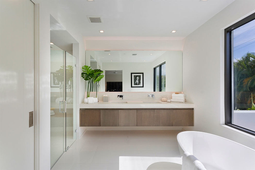 Design ideas for a contemporary master bathroom in Miami with flat-panel cabinets, medium wood cabinets, a freestanding tub, a curbless shower, white walls, an undermount sink, white floor, a hinged shower door and white benchtops.