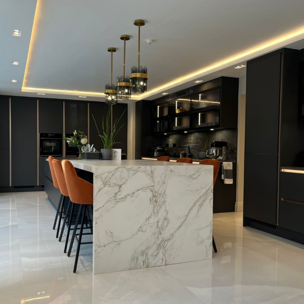 Inspiration for a large l-shaped gray floor eat-in kitchen remodel in London with an undermount sink, flat-panel cabinets, black cabinets, black backsplash, black appliances, an island and black countertops