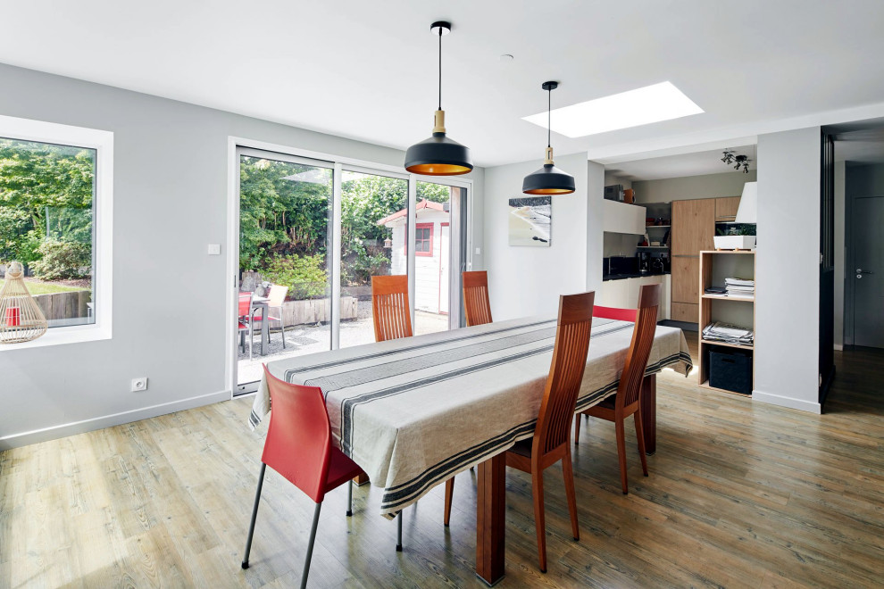 This is an example of a mid-sized contemporary open plan dining in Paris with white walls, medium hardwood floors, a wood stove, brown floor, recessed and brick walls.