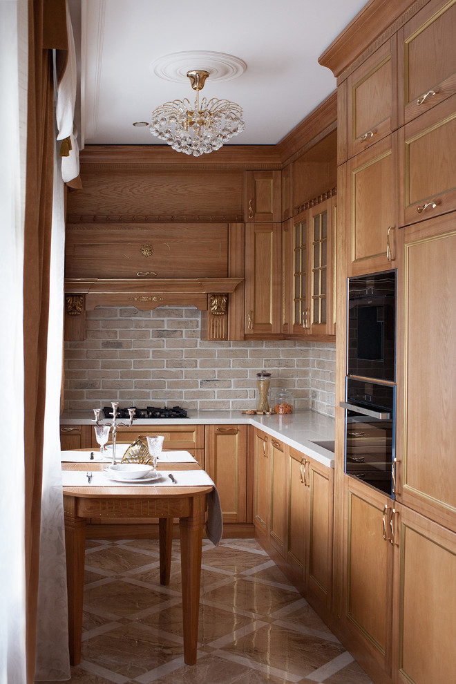 Design ideas for a small transitional l-shaped separate kitchen in Moscow with recessed-panel cabinets, solid surface benchtops, beige splashback, brick splashback, black appliances, porcelain floors, no island, an undermount sink, light wood cabinets, beige floor and white benchtop.
