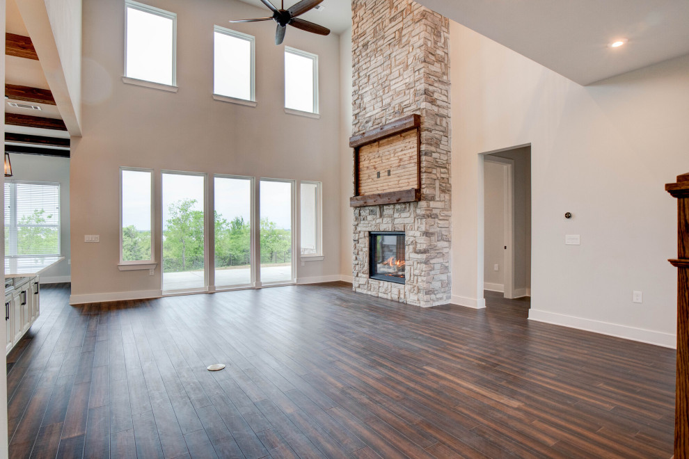 This is an example of a large traditional mezzanine living room in Dallas with dark hardwood flooring, a standard fireplace, a stone fireplace surround, a wall mounted tv and brown floors.