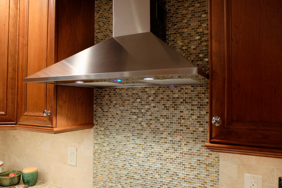 Eat-in kitchen - mid-sized transitional l-shaped medium tone wood floor eat-in kitchen idea in Boston with a farmhouse sink, flat-panel cabinets, medium tone wood cabinets, granite countertops, beige backsplash, subway tile backsplash, stainless steel appliances and an island