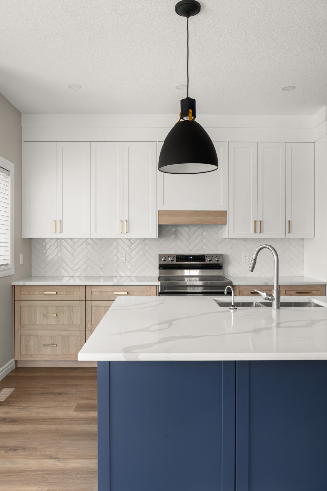 Design ideas for a large transitional single-wall eat-in kitchen in Calgary with an undermount sink, shaker cabinets, blue cabinets, quartz benchtops, white splashback, subway tile splashback, stainless steel appliances, vinyl floors, with island, brown floor and white benchtop.