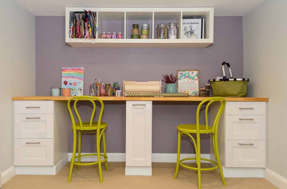 This is an example of a small transitional craft room in New York with purple walls, a built-in desk, no fireplace and vinyl floors.