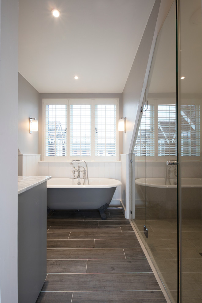 Cette photo montre une salle de bain principale nature avec des portes de placard grises, une baignoire indépendante et un mur gris.