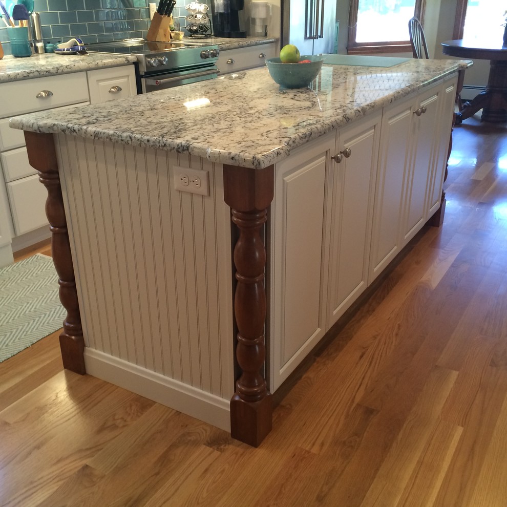 Example of a transitional u-shaped medium tone wood floor eat-in kitchen design in Boston with an undermount sink, raised-panel cabinets, white cabinets, granite countertops, blue backsplash, glass tile backsplash, stainless steel appliances and an island