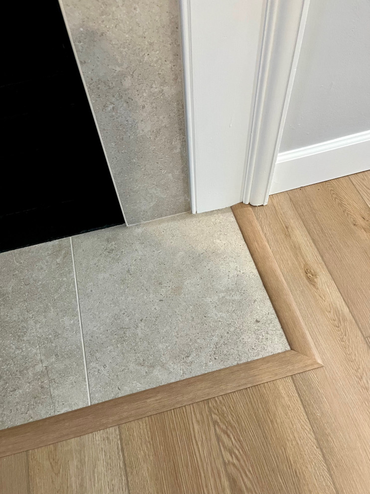 Mid-sized transitional vinyl floor and brown floor kitchen/dining room combo photo with white walls, a standard fireplace and a tile fireplace