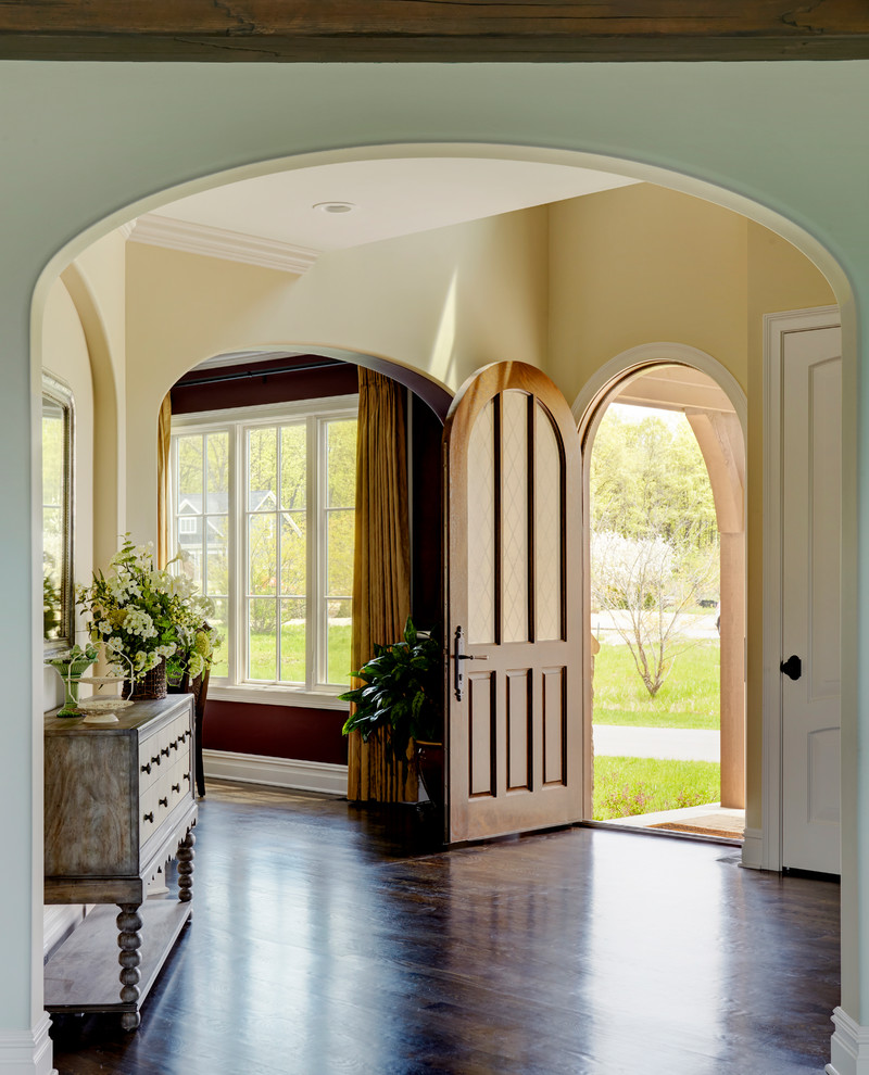 Inspiration for a large traditional front door in Chicago with yellow walls, dark hardwood floors, a single front door, a dark wood front door and brown floor.