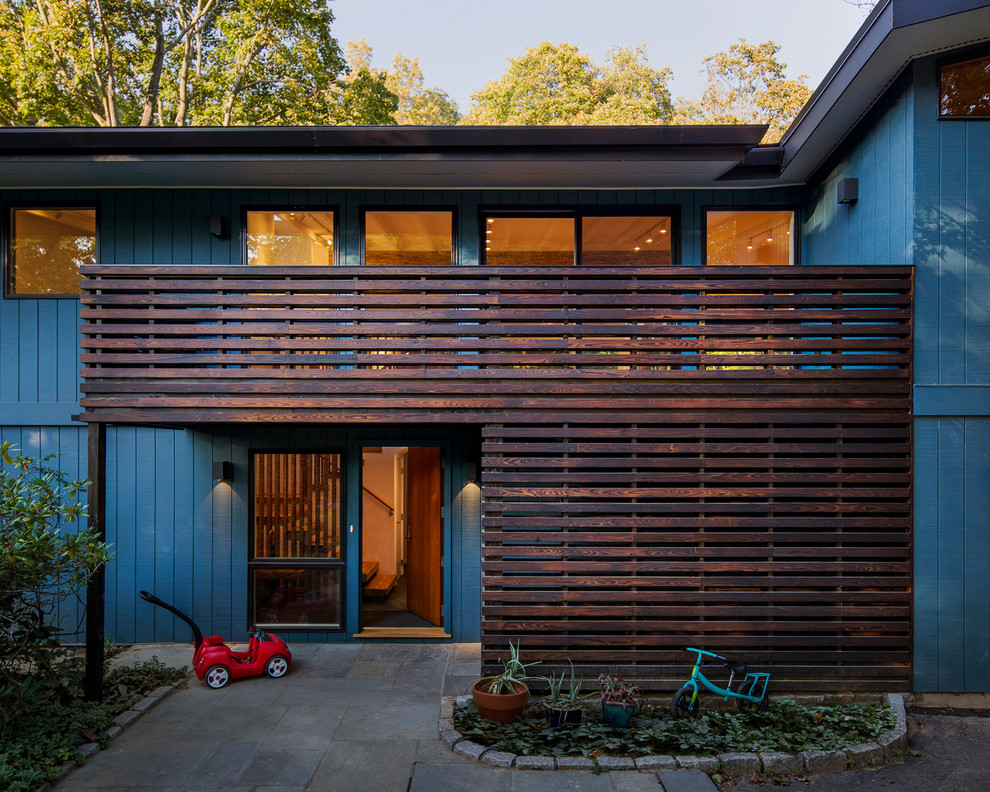 This is an example of a mid-sized modern two-storey blue house exterior in New York with wood siding and a shed roof.