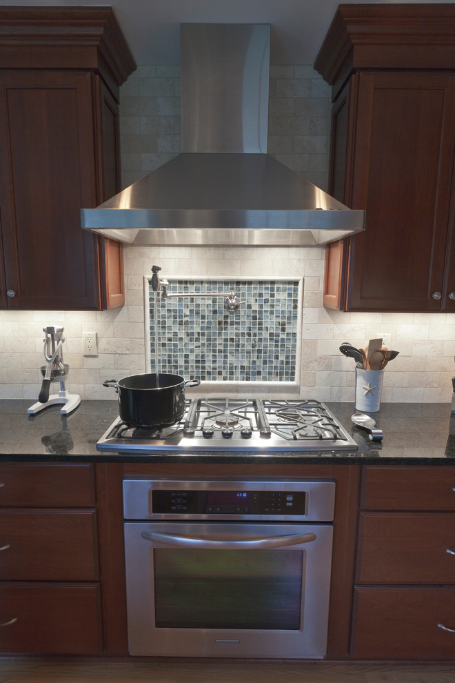 Mid-sized transitional l-shaped light wood floor eat-in kitchen photo in Bridgeport with an undermount sink, recessed-panel cabinets, medium tone wood cabinets, granite countertops, white backsplash, stone tile backsplash, stainless steel appliances and a peninsula