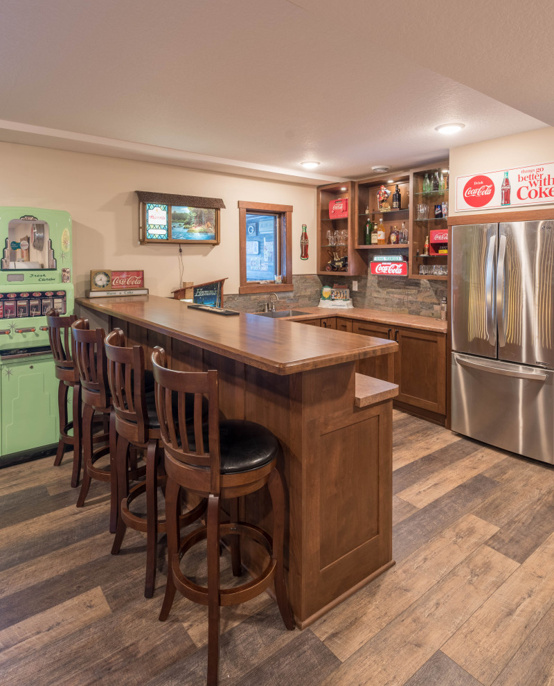 This is an example of a small arts and crafts u-shaped home bar in Minneapolis with an undermount sink, shaker cabinets, medium wood cabinets, laminate benchtops, multi-coloured splashback, stone tile splashback, linoleum floors, brown floor and brown benchtop.