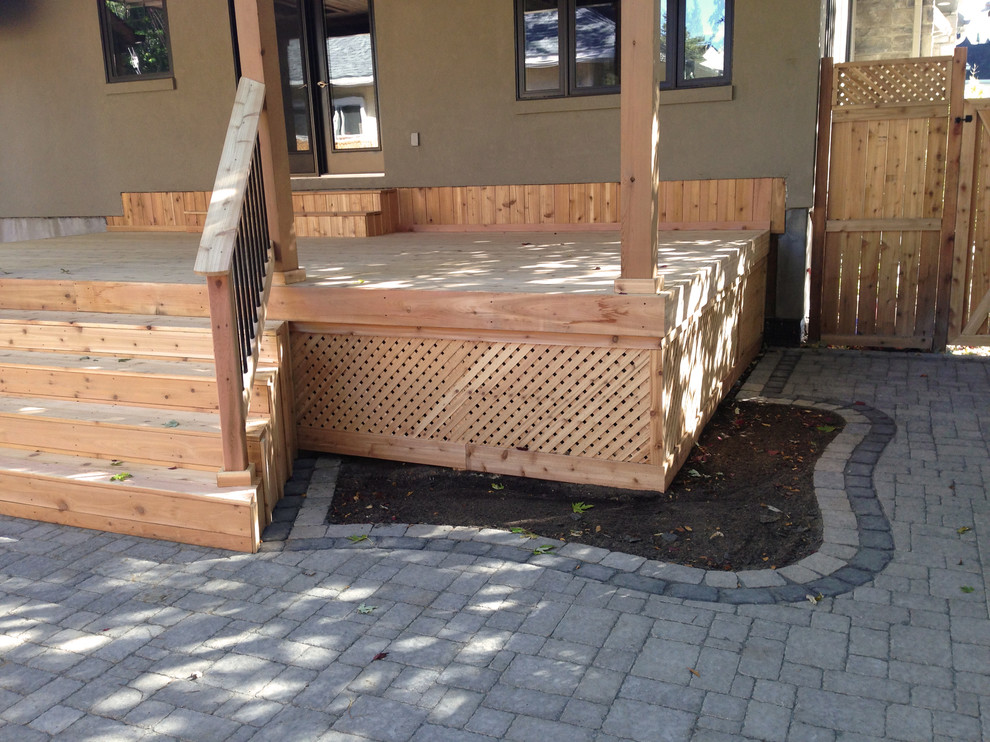 Example of a large minimalist backyard deck design in Ottawa with a roof extension