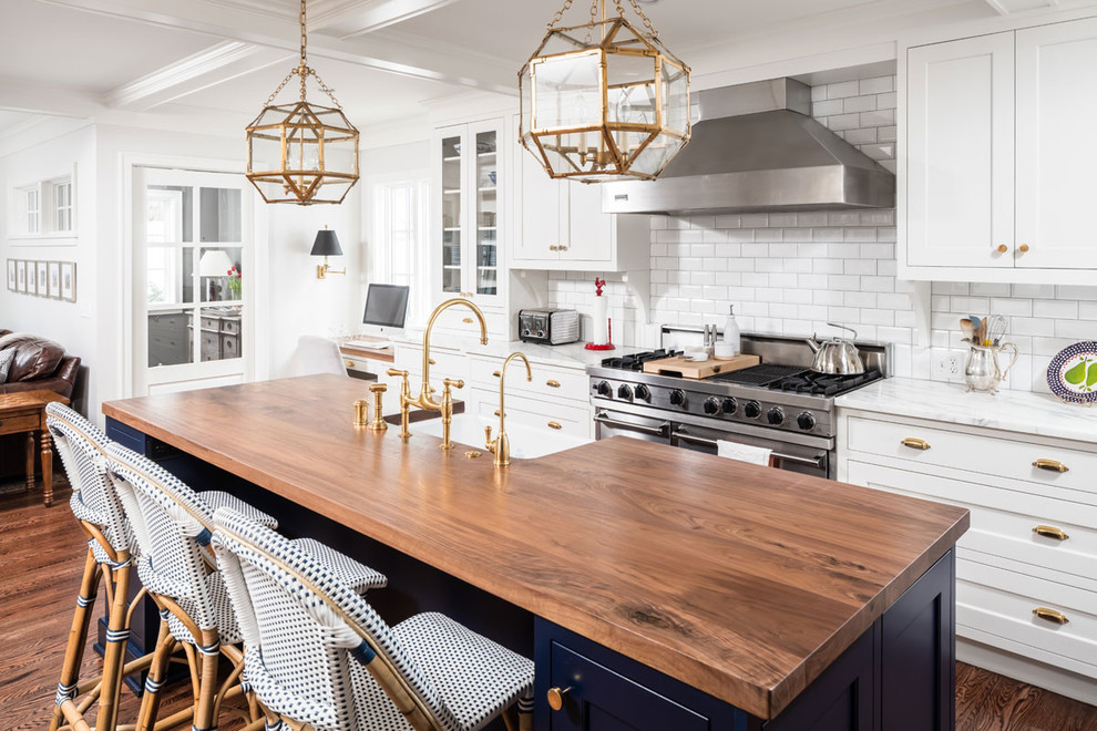 Photo of a traditional open plan kitchen in Minneapolis with wood benchtops, medium hardwood floors, with island, brown benchtop, a farmhouse sink, shaker cabinets, white cabinets, white splashback, subway tile splashback, coloured appliances and brown floor.