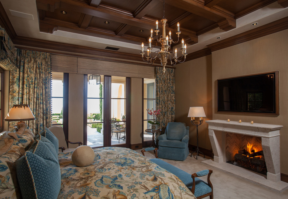 This is an example of a mediterranean master bedroom in Orange County with beige walls, carpet, a standard fireplace, a stone fireplace surround and grey floor.