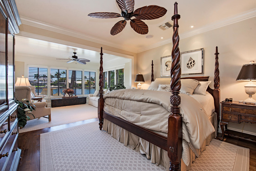 This is an example of a large tropical master bedroom in Miami with beige walls, dark hardwood floors and no fireplace.