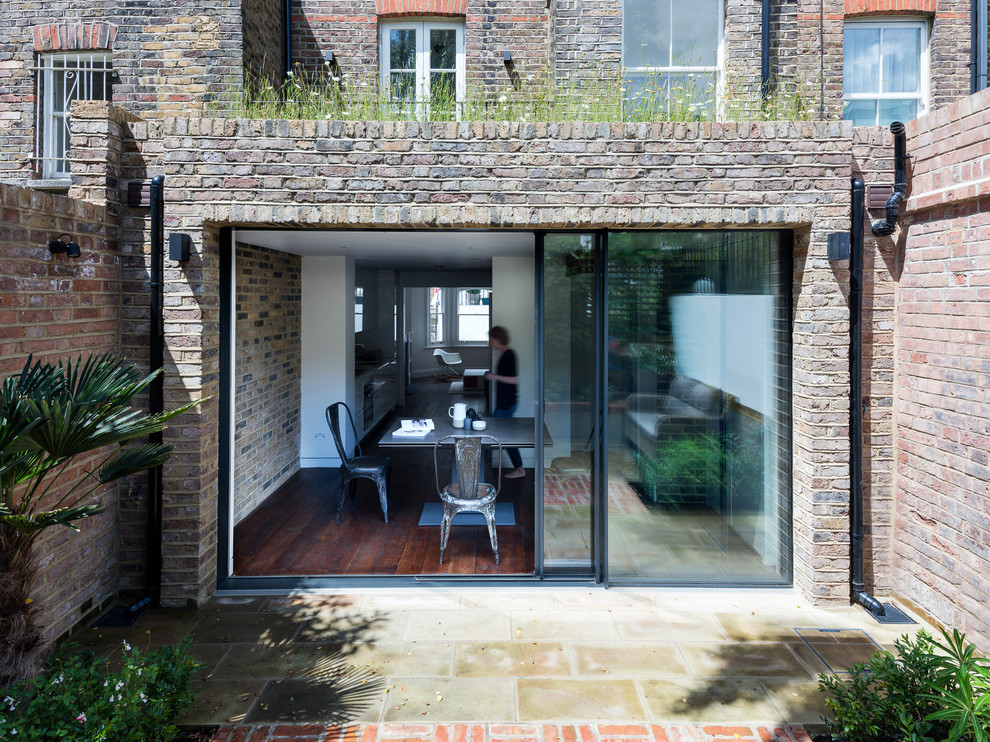 This is an example of a small contemporary two-storey brick exterior in London with a flat roof.