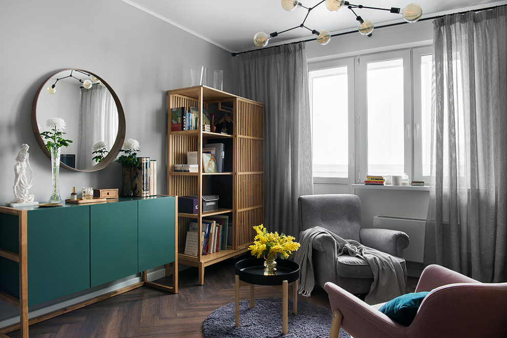 Пример оригинального дизайна: серо-белая гостиная комната среднего размера в современном стиле с с книжными шкафами и полками, серыми стенами, полом из ламината, зоной отдыха, коричневым полом и акцентной стеной