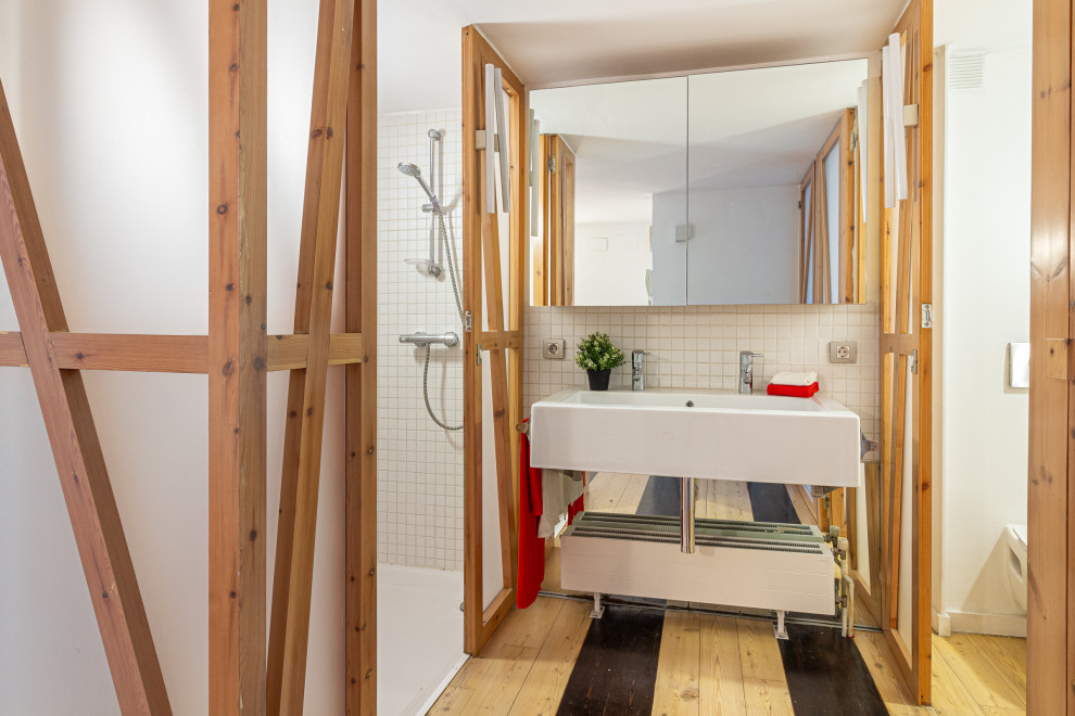 Design ideas for an urban bathroom in Barcelona with a built-in shower, white tiles, white walls, light hardwood flooring, a trough sink, multi-coloured floors and double sinks.