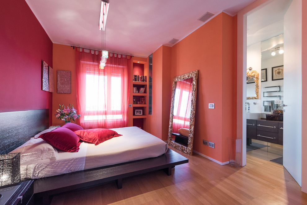 Design ideas for a mid-sized contemporary master bedroom in Milan with red walls and light hardwood floors.