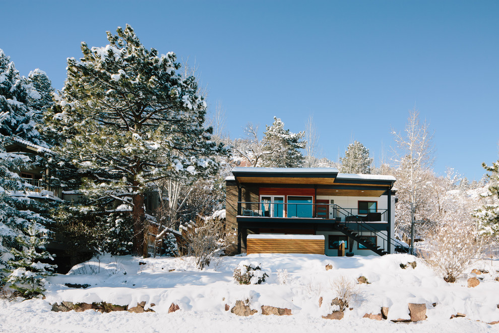 Design ideas for a midcentury white house exterior in Denver with a flat roof and mixed siding.