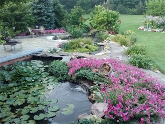 Design ideas for a mid-sized mediterranean backyard partial sun garden in Columbus with with pond and concrete pavers.