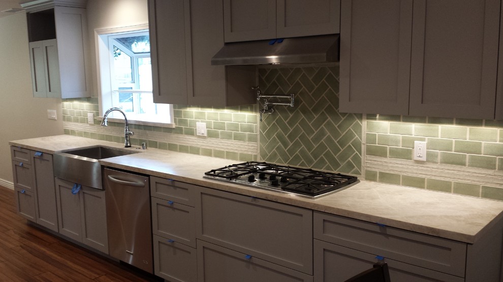 Mid-sized transitional galley medium tone wood floor eat-in kitchen photo with a farmhouse sink, shaker cabinets, white cabinets, granite countertops, green backsplash, glass tile backsplash, stainless steel appliances and no island