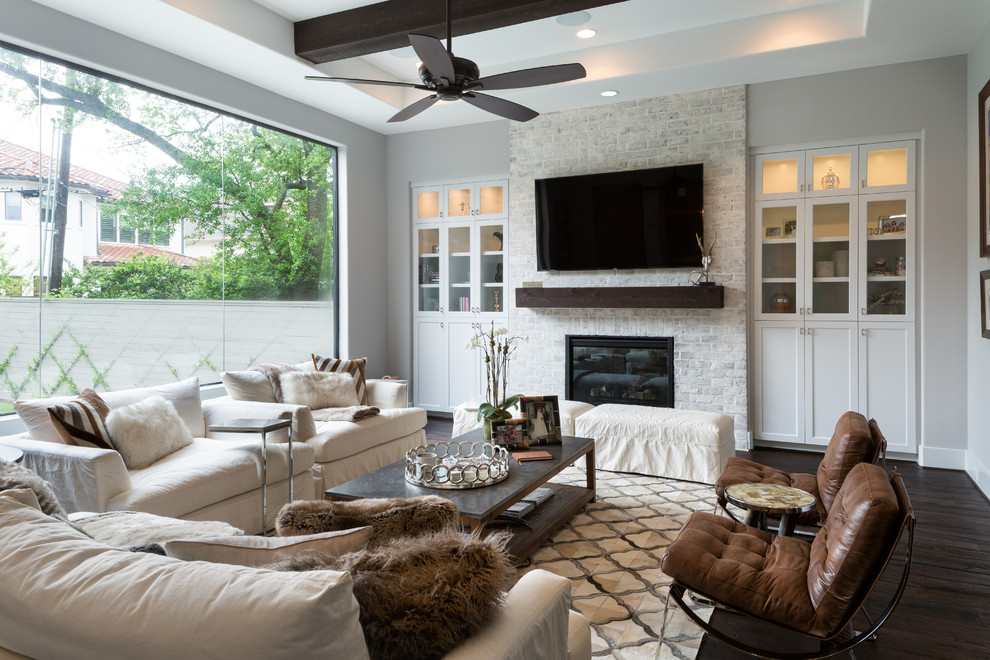 Inspiration for a transitional open concept living room in Houston with grey walls, dark hardwood floors, a brick fireplace surround, a wall-mounted tv and a standard fireplace.
