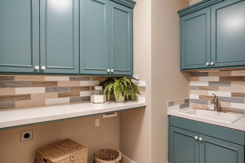Design ideas for a transitional l-shaped dedicated laundry room in Seattle with a drop-in sink, shaker cabinets, blue cabinets, laminate benchtops, grey walls and a side-by-side washer and dryer.