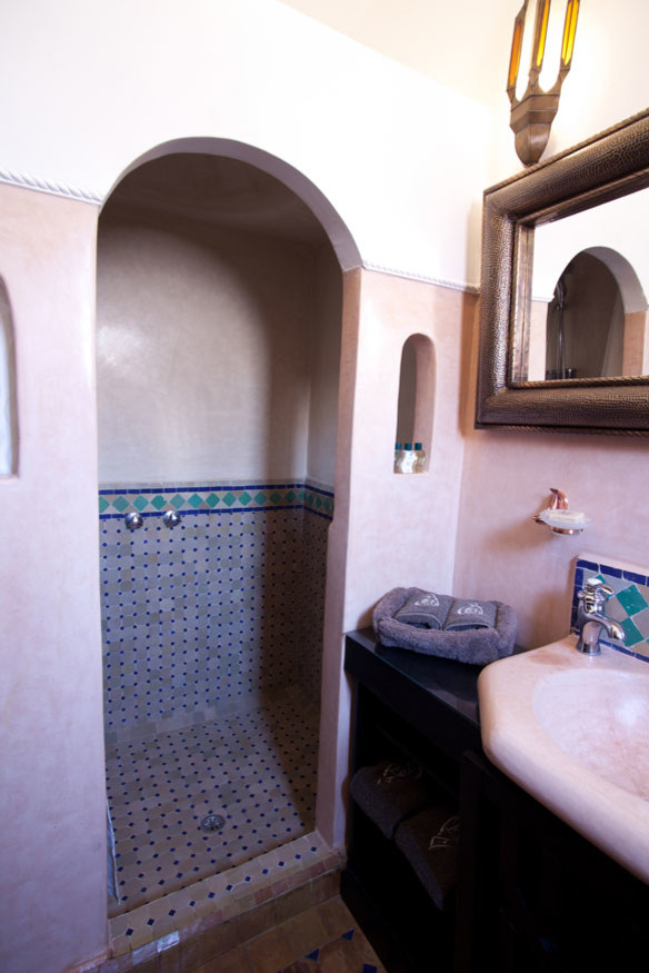 Mid-sized mediterranean 3/4 bathroom in Other with a curbless shower, a one-piece toilet, multi-coloured tile, terra-cotta tile, beige walls, terra-cotta floors, an integrated sink and concrete benchtops.