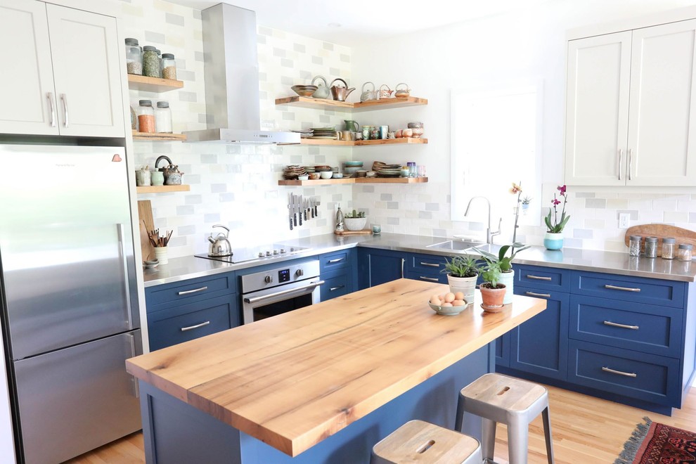 Open concept kitchen - mid-sized transitional l-shaped light wood floor and beige floor open concept kitchen idea with an integrated sink, shaker cabinets, blue cabinets, stainless steel countertops, white backsplash, ceramic backsplash, stainless steel appliances, an island and gray countertops