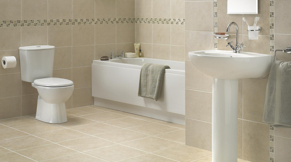 Small contemporary bathroom in Hampshire with a wall-mount sink, a drop-in tub, a two-piece toilet, beige tile and ceramic floors.
