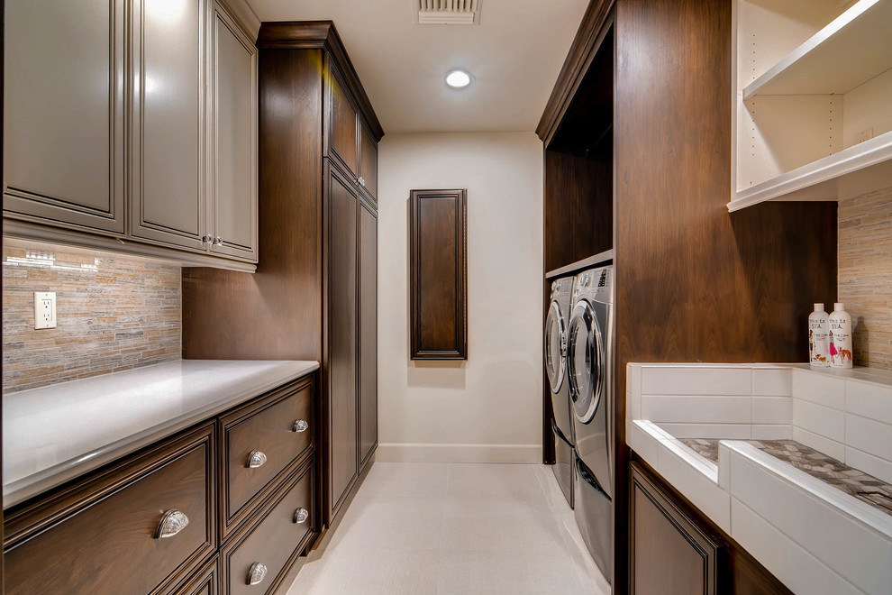 Design ideas for a large eclectic galley utility room in Phoenix with an utility sink, raised-panel cabinets, quartz benchtops, white walls, porcelain floors, a side-by-side washer and dryer, beige floor and dark wood cabinets.