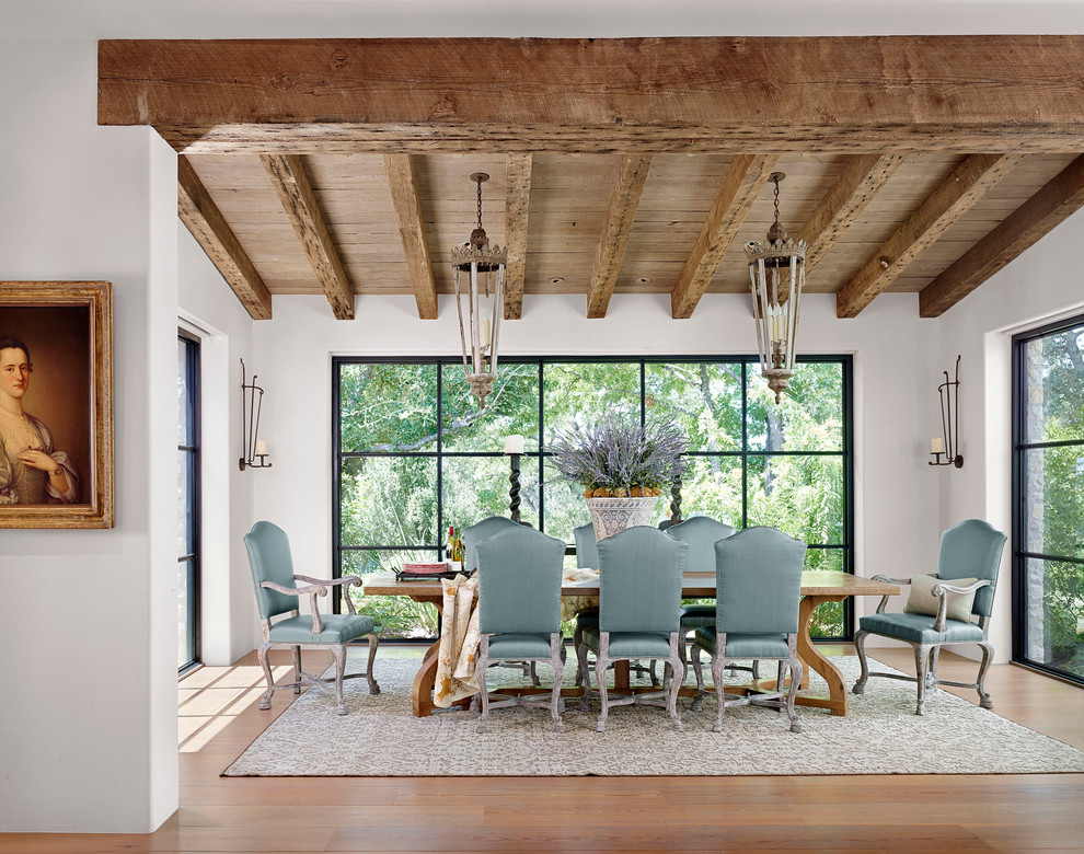 This is an example of a mediterranean dining room in Austin with white walls and medium hardwood floors.