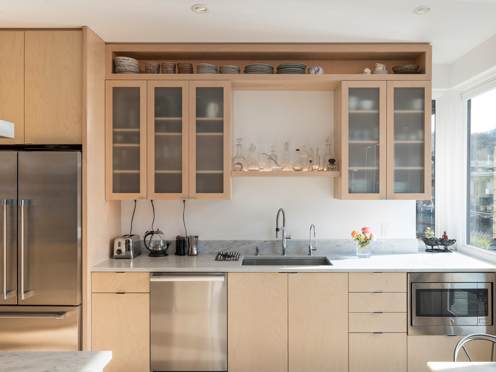 Beach style kitchen in Seattle with an undermount sink, flat-panel cabinets, light wood cabinets, stainless steel appliances and grey benchtop.