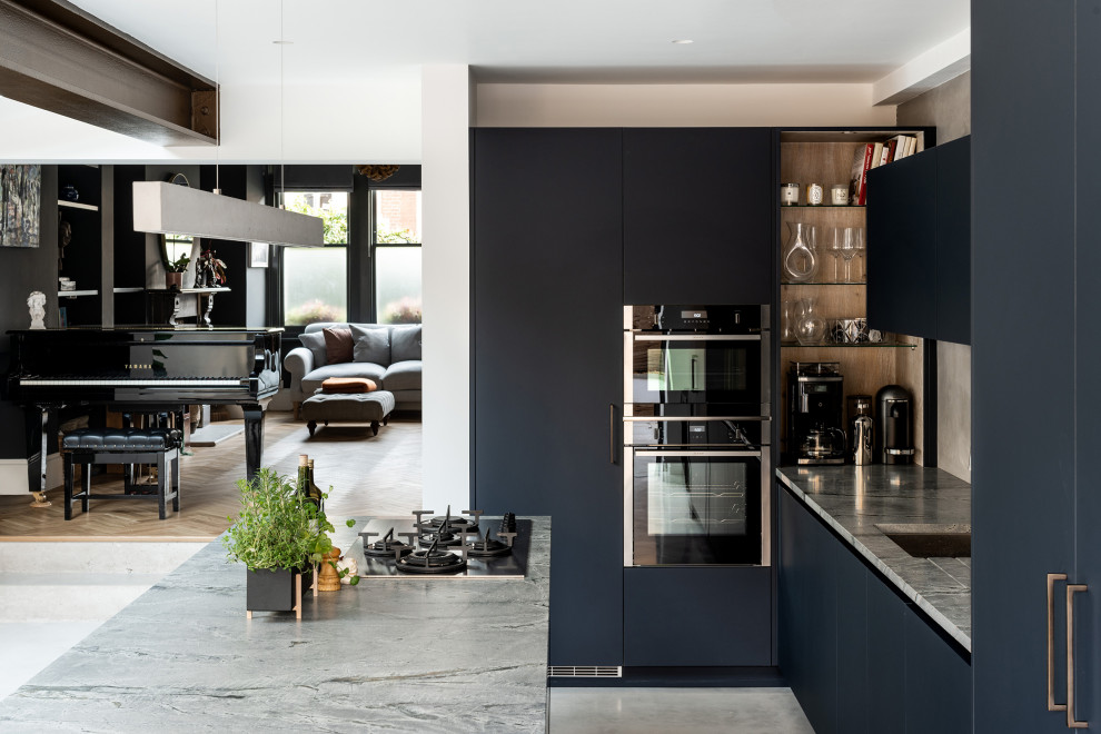 Photo of a contemporary l-shaped eat-in kitchen in London with flat-panel cabinets, blue cabinets, stainless steel appliances, concrete floors and with island.