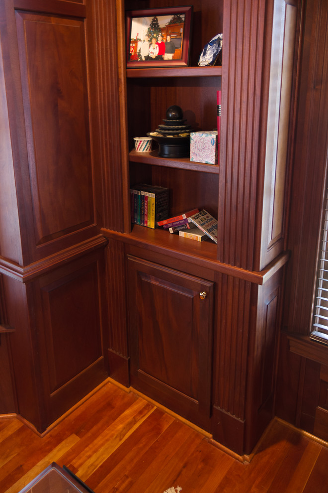 Inspiration for a mid-sized traditional home office in Raleigh with medium hardwood floors, no fireplace, a freestanding desk, a library and brown walls.