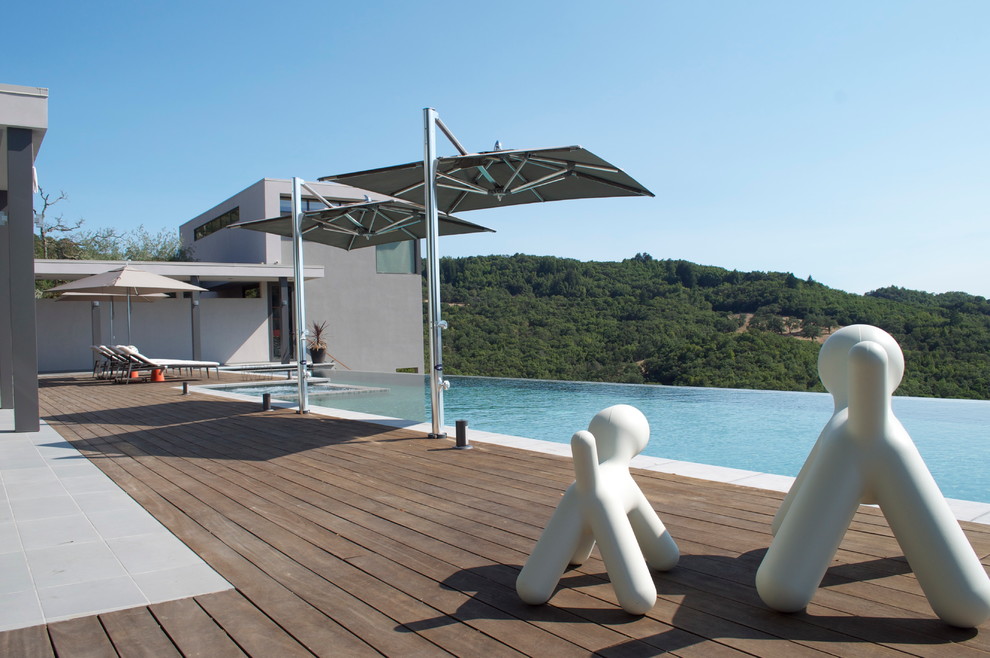 This is an example of a large modern backyard rectangular infinity pool in San Francisco with a hot tub and decking.