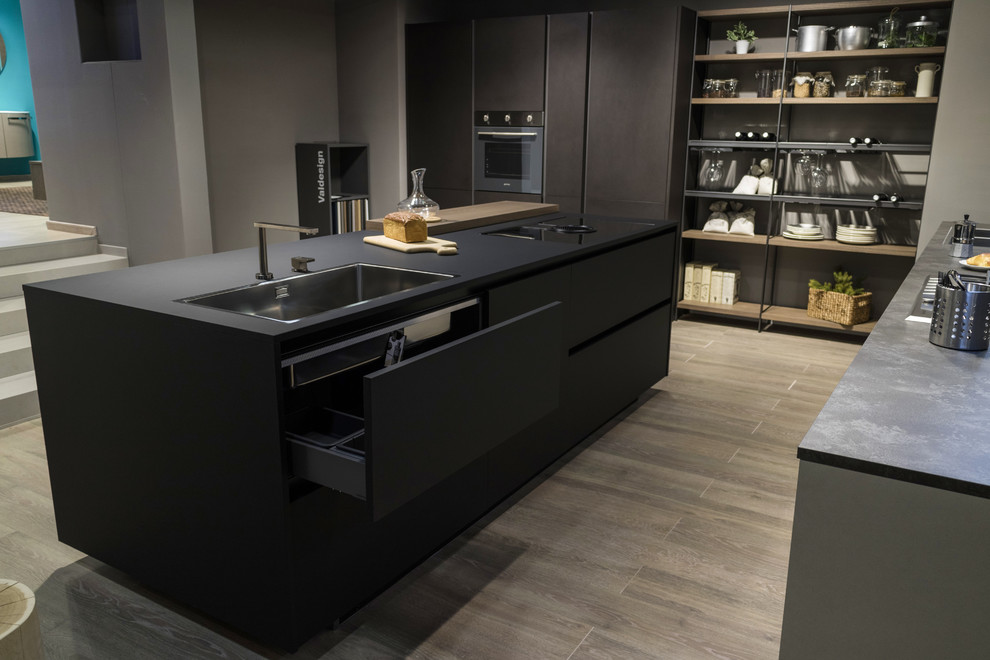 Inspiration for a mid-sized modern single-wall open plan kitchen in Naples with a drop-in sink, flat-panel cabinets, black cabinets, grey splashback, stainless steel appliances, bamboo floors and with island.