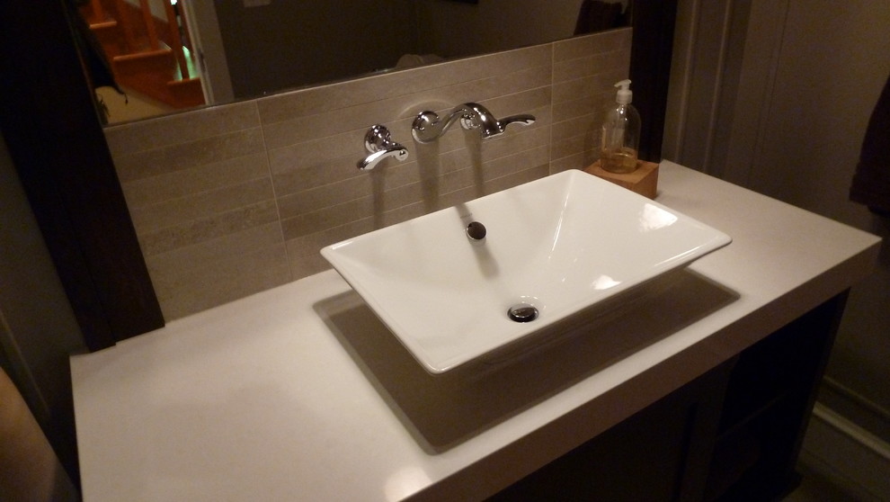 This is an example of a mid-sized arts and crafts powder room in Vancouver with flat-panel cabinets, black cabinets, beige walls and a vessel sink.