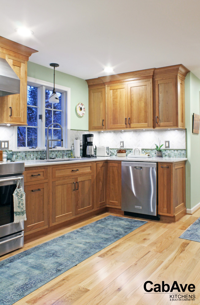 Example of a large transitional u-shaped light wood floor and beige floor open concept kitchen design with an undermount sink, recessed-panel cabinets, light wood cabinets, quartz countertops, green backsplash, mosaic tile backsplash, stainless steel appliances and a peninsula