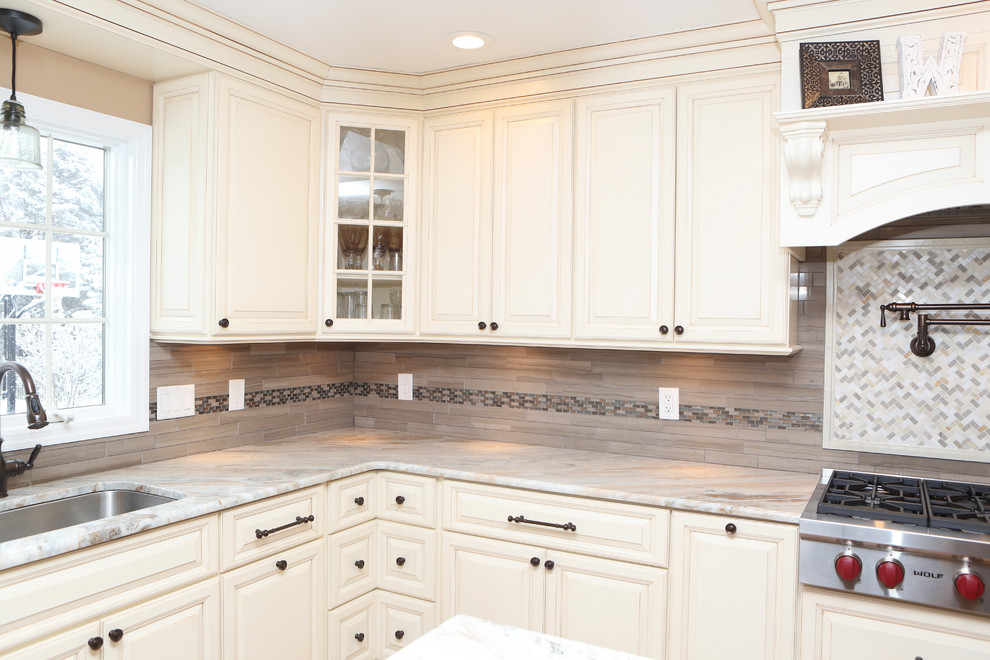 Inspiration for a large transitional u-shaped light wood floor eat-in kitchen remodel in Newark with an undermount sink, raised-panel cabinets, distressed cabinets, granite countertops, brown backsplash, mosaic tile backsplash, stainless steel appliances and an island