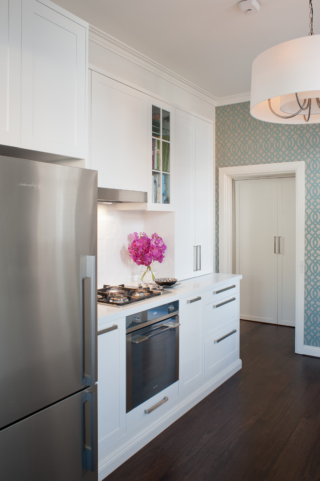 Mid-sized transitional galley eat-in kitchen in Sydney with an undermount sink, shaker cabinets, white cabinets, quartz benchtops, white splashback, porcelain splashback, stainless steel appliances, dark hardwood floors, no island and brown floor.