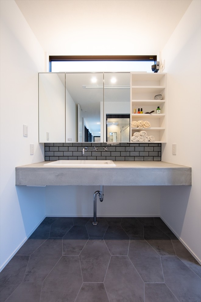 Photo of a mid-sized midcentury powder room in Other with open cabinets, white cabinets, gray tile, slate floors, concrete benchtops, grey floor, grey benchtops, white walls and a vessel sink.