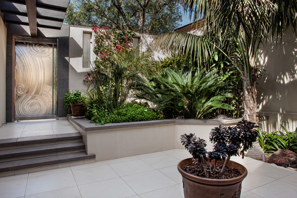 Large tropical courtyard partial sun formal garden in San Diego with a container garden and concrete pavers for summer.