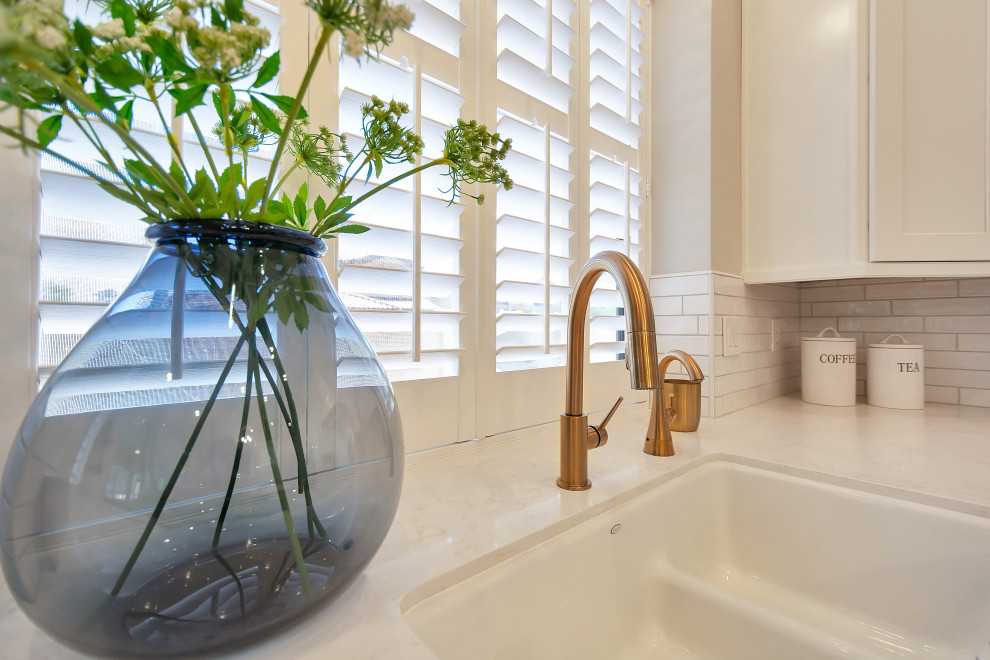 Example of a large transitional u-shaped open concept kitchen design in Phoenix with a farmhouse sink, shaker cabinets, white cabinets, quartz countertops, white backsplash, subway tile backsplash, stainless steel appliances, an island and white countertops