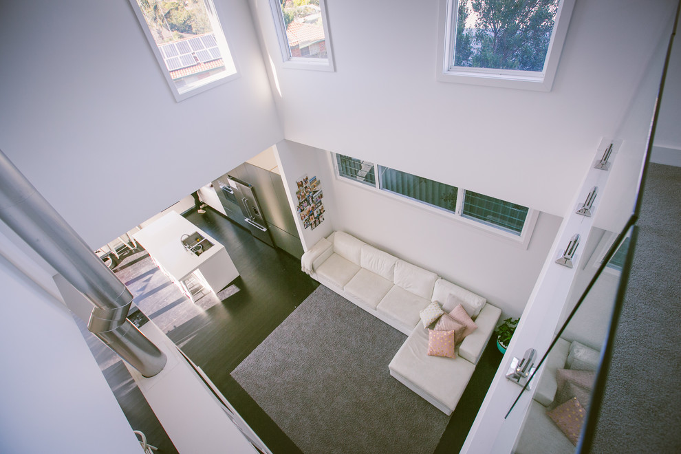 Contemporary open concept living room in Sydney with white walls, dark hardwood floors, a two-sided fireplace, a plaster fireplace surround and a built-in media wall.