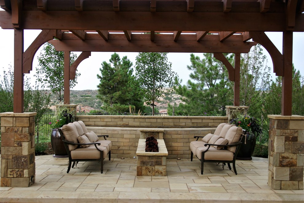 Design ideas for a mid-sized mediterranean backyard patio in Denver with a fire feature, natural stone pavers and a pergola.