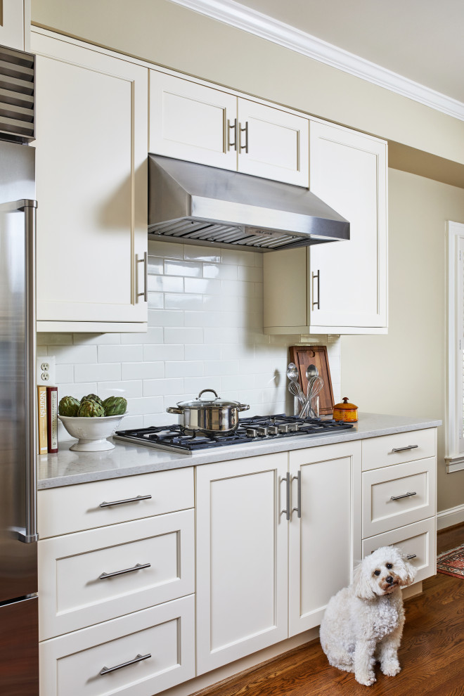 Inspiration for a mid-sized transitional u-shaped medium tone wood floor and brown floor enclosed kitchen remodel in DC Metro with an undermount sink, shaker cabinets, white cabinets, quartzite countertops, white backsplash, subway tile backsplash, stainless steel appliances, a peninsula and gray countertops