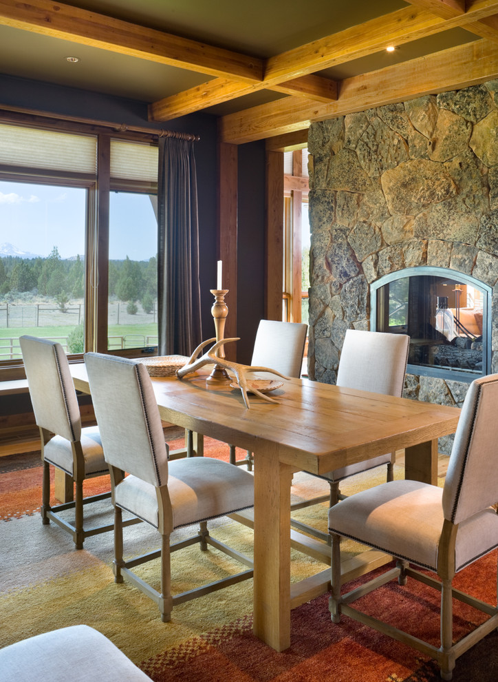 This is an example of a country dining room in Portland with a two-sided fireplace and a stone fireplace surround.